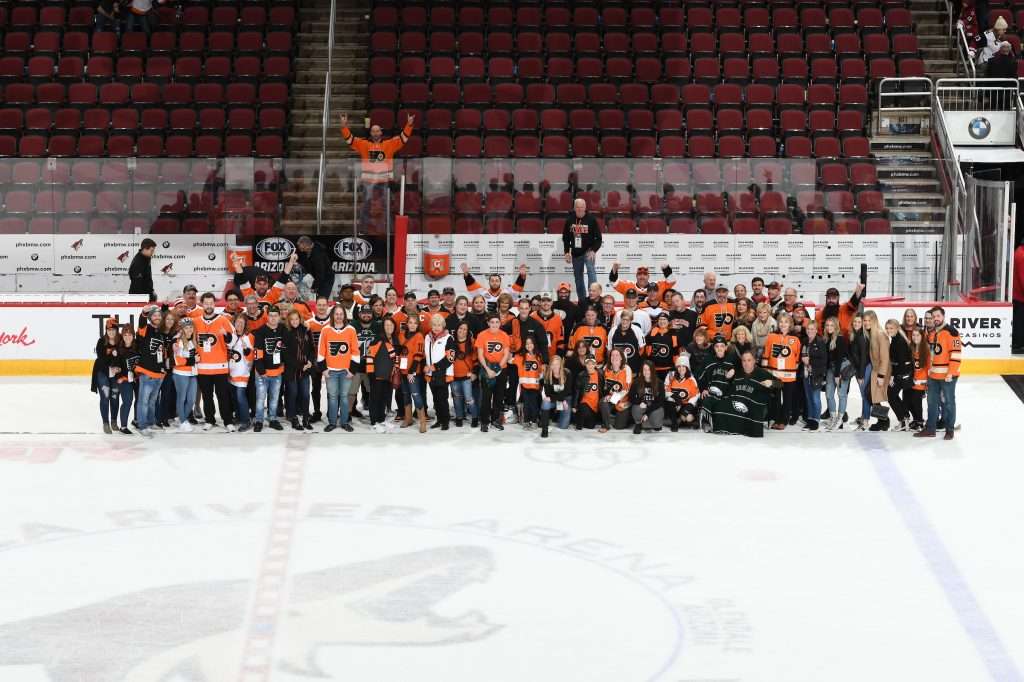 A big group of Philadelphia Flyers fans posing at center ice. In the Gila River Arena in Phoenix. This was post game and from the group Phans of Philly. A traveling fan group